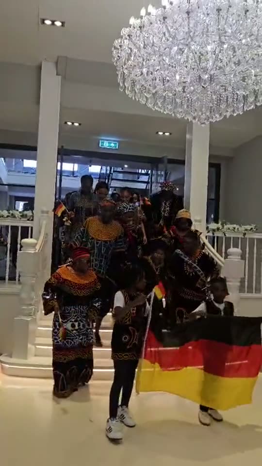 Team Germany enters the hall at the Almere 2026 convention, Toghu and Ndop regalia behind the German flag.